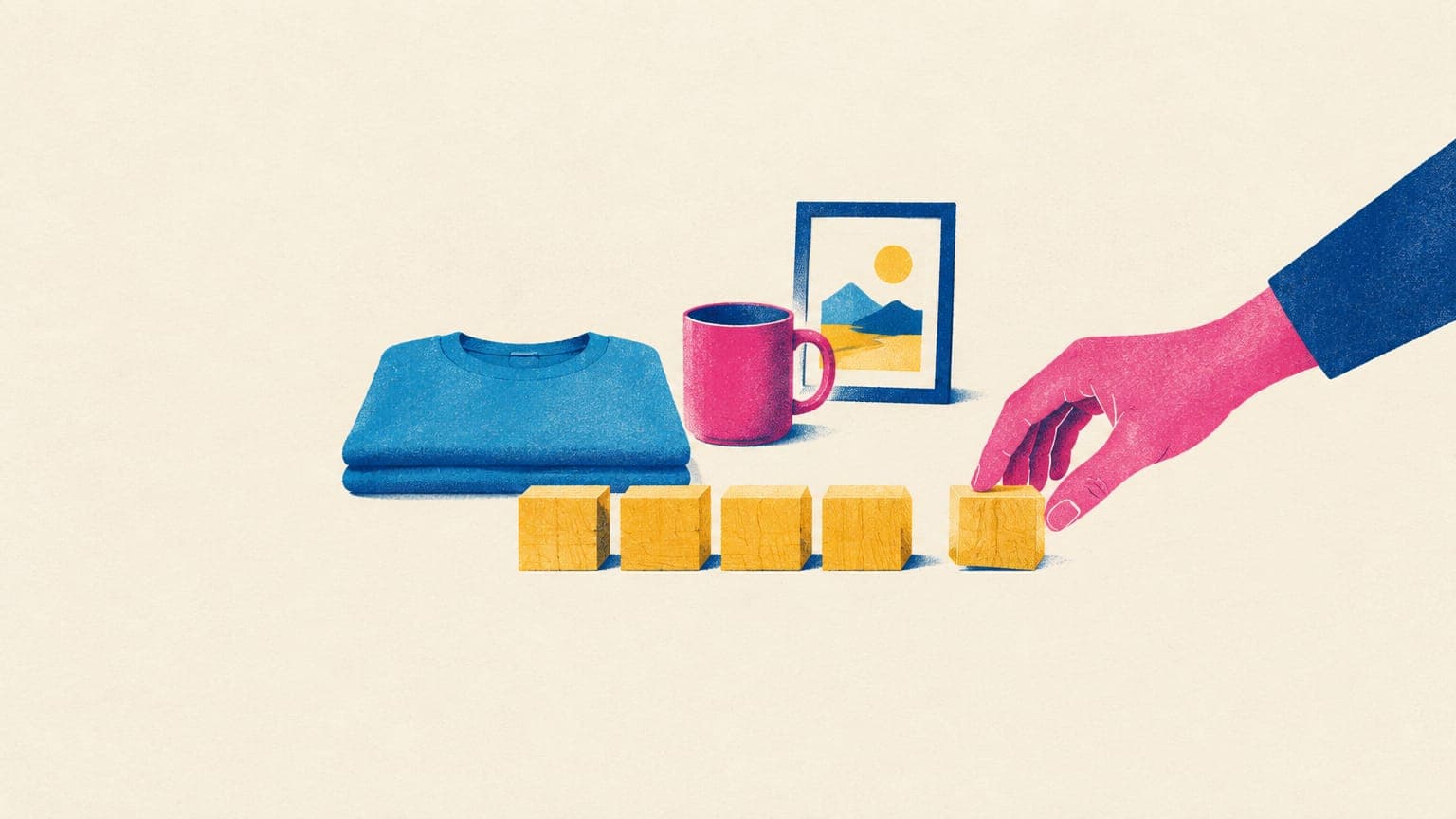 Hand placing blank wooden blocks in a row in front of a folded t-shirt, a mug and a small framed print