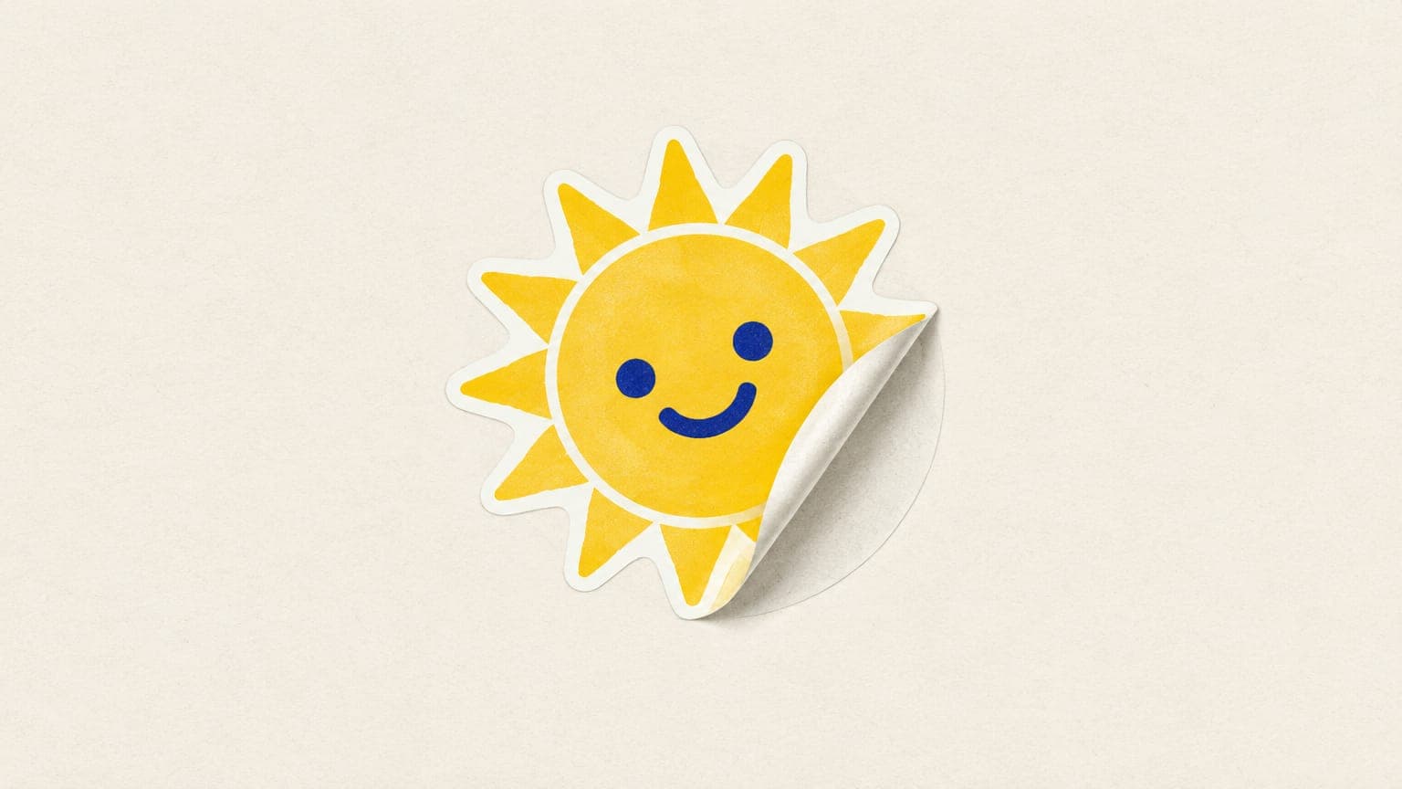 A sun-shaped vinyl sticker being peeled off its backing sheet, showing its cut edge and white border